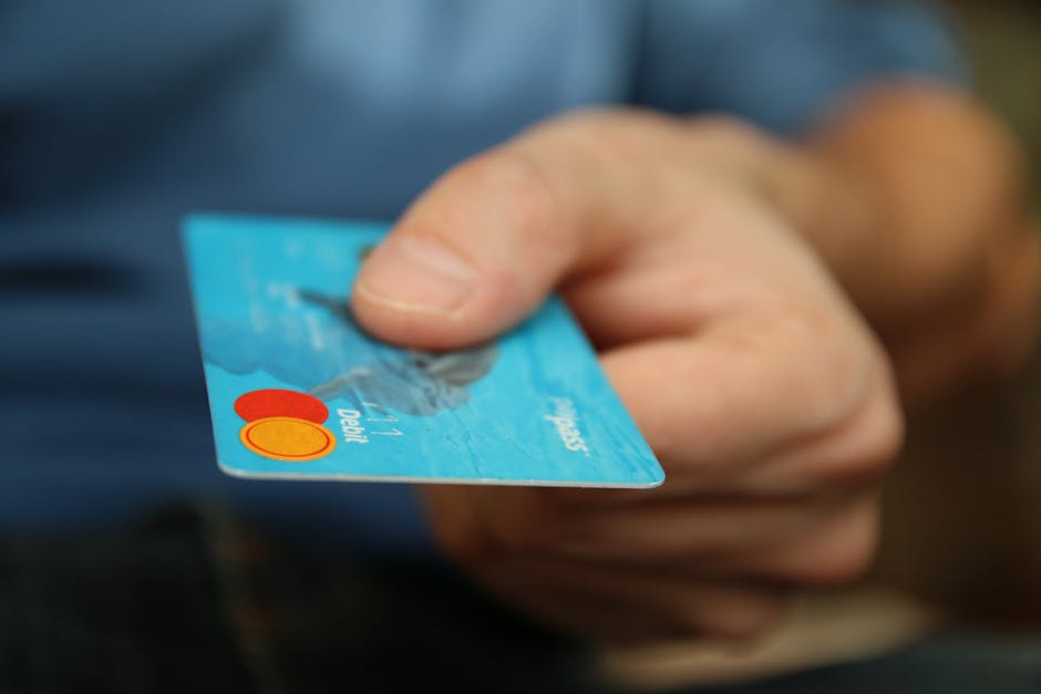 Close-up of a person holding a blue credit card, financial transaction in progress