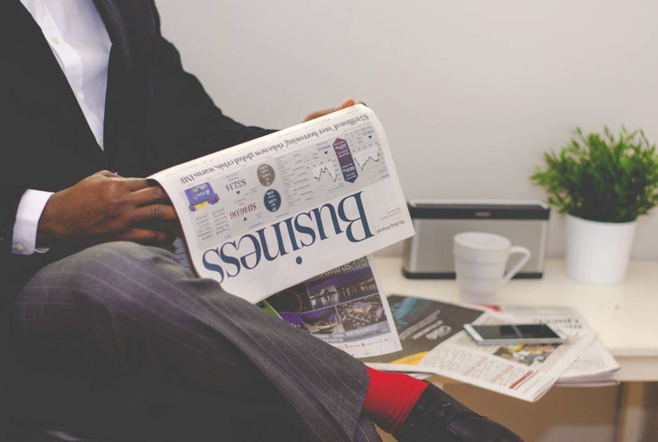 Businessman reading a newspaper with the headline 'Business', sitting at a table with a coffee cup and documents