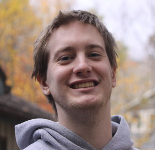 Portrait of Charles Hall smiling outdoors in a casual hoodie